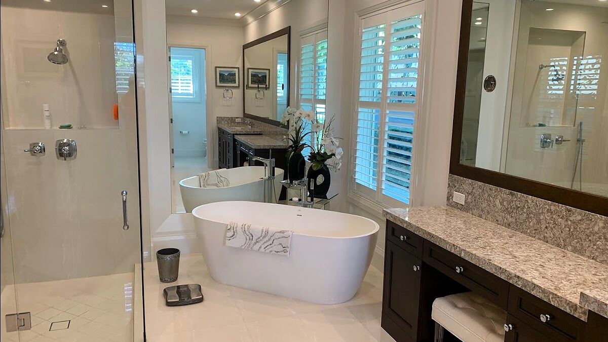 Original MGS frameless glass enclosure beside a freestanding tub