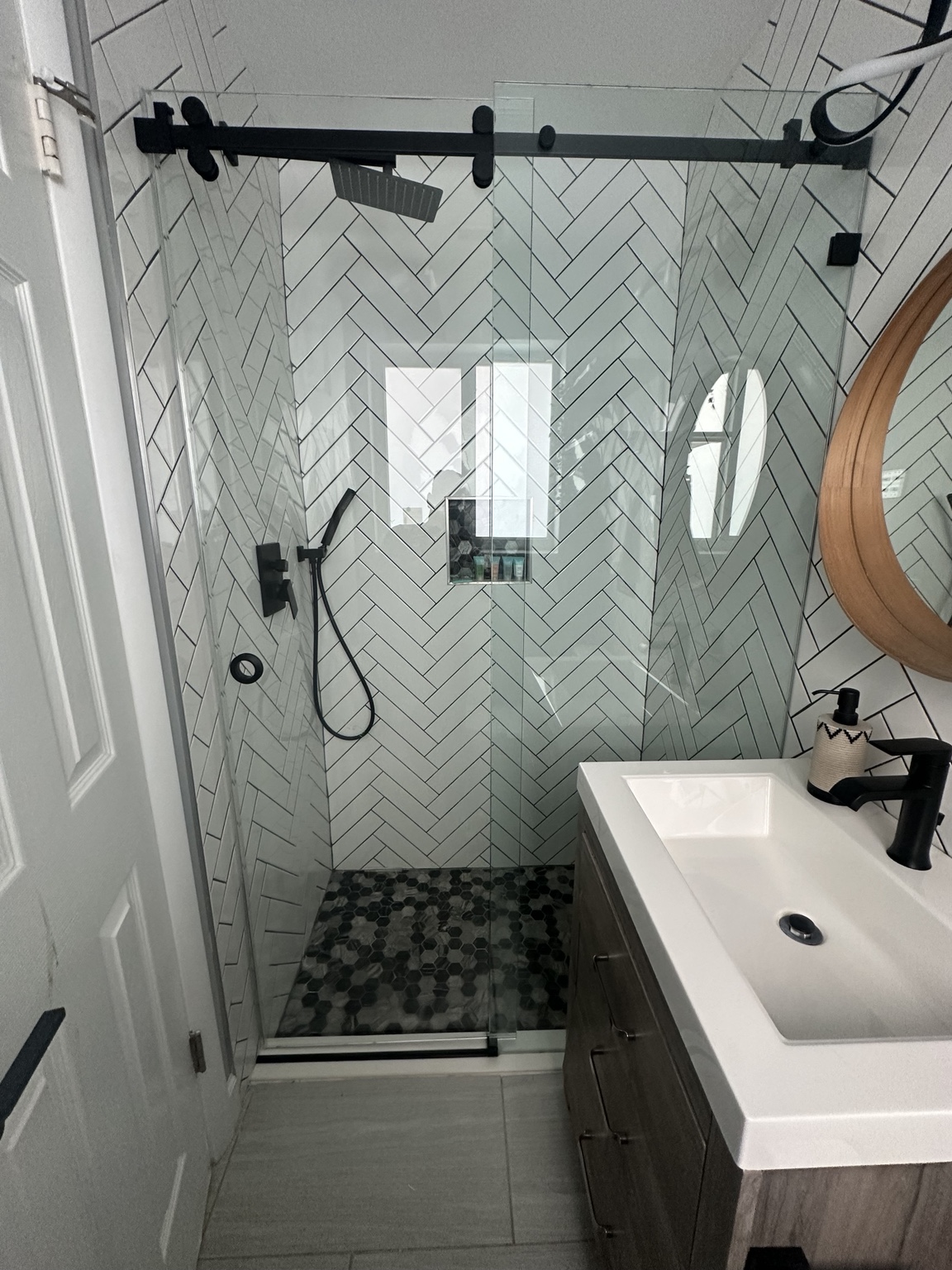 Original My Glass Shower installation with matte-black sliding shower hardware and white herringbone tile